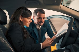 A woman and a man looking at documents in a car
