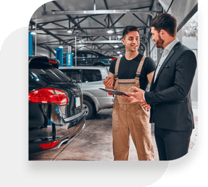 Happy car mechanic conversing with a client in an auto repair shop.
