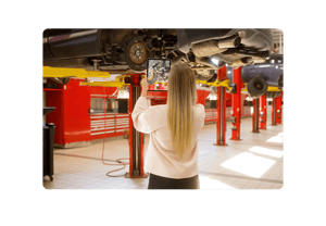 Technician filming a car being repaired in a service department with a tablet