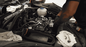 The inside of a hood of a car being repaired by a technician